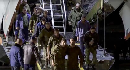 En esta foto difundida por el Servicio de Prensa del Ministerio de Defensa ruso el jueves 22 de septiembre de 2022, un grupo de prisioneros de guerra rusos abandona un avión militar tras ser liberados.