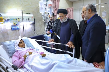 En esta foto difundida por la Oficina de la Presidencia de Irán, el presidente iraní Ebrahim Raisi visita a una mujer herida en la explosión de bomba del miércoles en la ciudad de Kerman.