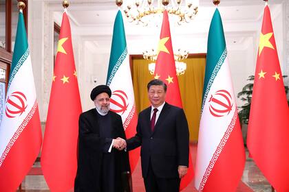 En esta foto difundida por la web oficial de la oficina de la Presidencia iraní, el presidente Ebrahim Raisi estrecha la mano de su homólogo chino Xi Jinping en una ceremonia oficial de bienvenida en Pekín, el martes 14 de febrero de 2023. 