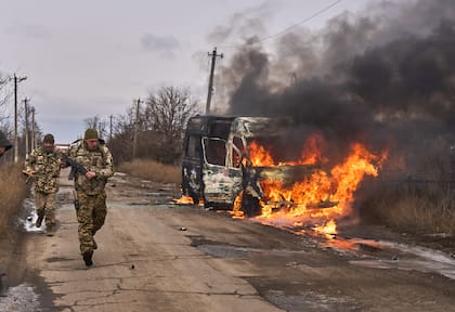 En esta foto distribuida por la 10ma Brigada de Montaña "Edelweiss", de Ucrania, soldados ucranianos pasan junto a un bus impactado por un dron ruso cerca de Bajmut, región de Donetsk, Ucrania, 23 de noviembre de 2023. (Shandyba Mykyta, 10ma Brigada de Montaña "Edelweiss", via AP)