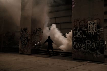En esta foto, los manifestantes corren mientras se despliega gas lacrimógeno en los escalones del edificio del Tribunal de Distrito de Estados Unidos el 17 de julio de 2020 en Portland, Oregon