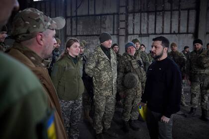 En esta foto proporcionada por la Oficina de Prensa Presidencial de Ucrania, el presidente ucraniano Volodimir Zelensky habla con soldados en una posición cerca de Bakhmut, región de Donetsk, Ucrania, el miércoles 22 de marzo de 2023.