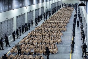 En esta foto proporcionada por la oficina de prensa de la presidencia de El Salvador, los presos identificados por las autoridades como pandilleros están sentados en el piso de la prisión del Centro de Confinamiento contra el Terrorismo en Tecoluca, El Salvador, el miércoles 15 de marzo de 2023.