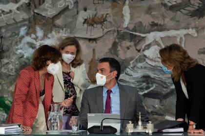 En esta foto provista por el gobierno español en Madrid, el presidente del gobierno, Pedro Sánchez, centro, conversa con tres ministras durante una reunión del consejo de ministros en el Palacio de la Moncloa, Madrid, martes 22 de junio de 2021