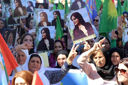En esta foto provista por la agencia kurda Hawar News Agency, mujeres kurdas llevan retratos de la iraní Mahsa Amini en una protesta por su asesinato en Irán, realizada en la ciudad iraquí de Qamishli el 26 de septiembre del 2022. 