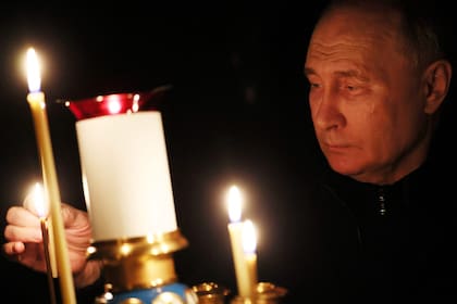 En esta fotografía de la piscina distribuida por la agencia estatal rusa Sputnik, el presidente ruso Vladimir Putin enciende una vela durante su visita a una iglesia de la residencia estatal Novo-Ogaryovo en las afueras de Moscú el 24 de marzo de 2024, durante el luto nacional
