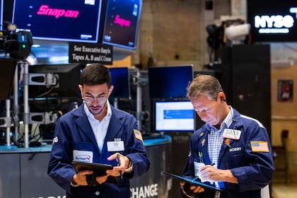 En esta fotografía proporcionada por la Bolsa de Valores de Nueva York, los corredores Orel Partush (izquierda) y Robert Charmak trabajan. (David L. Nemec/New York Stock Exchange via AP)
