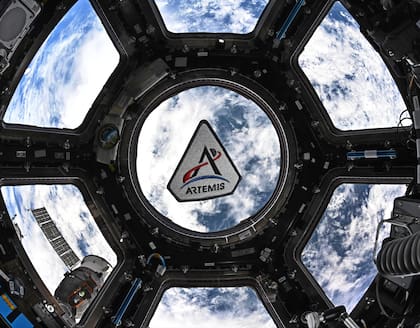 En esta fotografía proporcionada por la NASA, se observa un parche del programa Artemis flotando en la cúpula de la Estación Espacial Internacional, el 30 de marzo de 2026