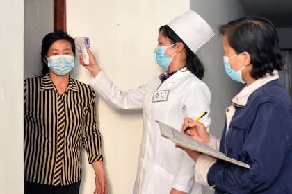 En esta imagen de archivo, distribuida por el gobierno de Corea del Norte, una doctora toma la temperatura a un residente para tratar de frenar la propagación del coronavirus, en Pyongyang, Corea del Norte, el 17 de mayo de 2022. (Agencia Central de Noticias de Corea/Korea News Service vía AP, archivo)