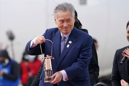 En esta imagen de archivo, tomada el 20 de marzo de 2020, el entonces presidente del comité organizador de los Juegos Olímpicos de Tokio 2020, Yoshiro Mori, lleva la llama olímpica a su llegada a la base aérea de Matsushima, en Higashimatsushima, en la prefectura de Miyagi, al norte de Tokio. (AP Foto/Eugene Hoshiko, archivo)