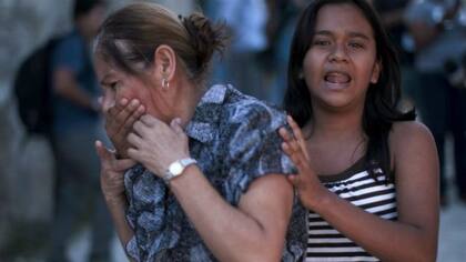 En esta imagen de febrero de 2016, una joven le cubría la boca a su madre, quien gritó tras enterarse de que su hijo había muerto en un tiroteo en la ciudad de Zaragoza, en El Salvador