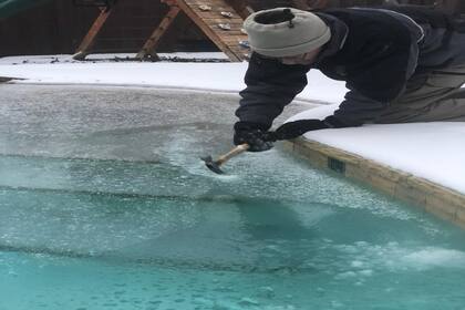 En esta imagen, el esposo de María Andrea Busico-Flight intenta romper la capa de hielo de la pileta, congelada por las bajas temperaturas