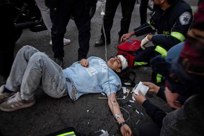 En esta imagen obtenida de la agencia de noticias iraní ISNA el 3 de marzo de 2026, rescatistas asisten a una víctima tras un ataque contra un edificio en la plaza Enghelab, en Teherán