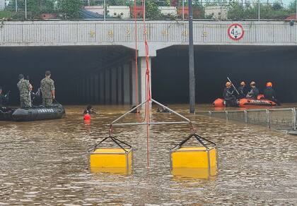 En esta imagen proporcionada por la Agencia Nacional de Bomberos de Corea del Sur, rescatistas buscan sobrevivientes en un túnel en una carretera inundada en Cheongju, Corea del Sur, el domingo 16 de julio de 2023.  
