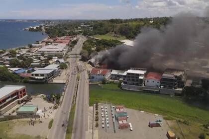 En esta imagen tomada de un video aéreo, el humo se eleva desde edificios en llamas durante una protesta en la capital de Honiara, Islas Salomón, el jueves 25 de noviembre de 2021.