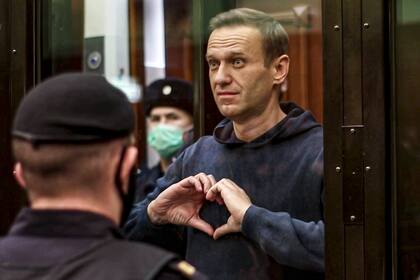 En esta imagen tomada de un video difundido por la Corte Municipal de Moscú el 2 de febrero de 2021, el líder opositor ruso Alexei Navalny hace un gesto de corazón con las manos mientras se encuentra de pie en el banquillo de los acusados durante una audiencia en la Corte Municipal de Moscú. (Corte Municipal de Moscú vía AP, Archivo)