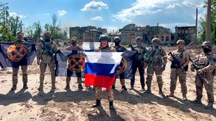 En esta imagen tomada de un vídeo y difundida por el Servicio de Prensa de Prigozhin el sábado 20 de mayo de 2023, Yevgeny Prigozhin, jefe de la compañía militar Wagner Group habla sosteniendo una bandera nacional rusa delante de sus soldados en Bakhmut, Ucrania.