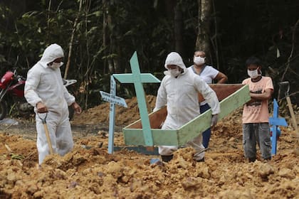 En esta imagen, tomada el 16 de abril de 2020, enterradores, vestidos con equipos de protección, preparan una tumba en el cementerio Nossa Senhora Aparecida para una mujer que se cree que murió por coronavirus, en Manaos, en el estado brasileño de Amazonas