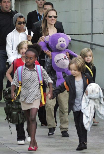 En esta imagen, tomada en Sidney, Ausatralia, en septiembre de 2013, la pequeña Shiloh viste una remera de color rojo y camina detrás de su hermana Zahara, un año mayor; en la foto también puede verse a los otros hijos de Jolie y Pitt: los mellizos Knox y Vivienne, Maddox y Pax Thien, que cubre su rostro con un oso de peluche