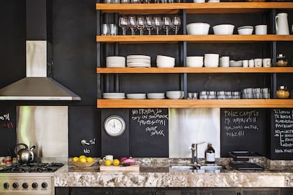 En este caso, la alzada se cubrió con pintura de pizarrón para anotar recetas o mensajes, pero se sumaron placas de acero inoxidable en los sectores con más desgaste.