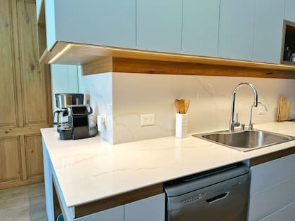 En este caso, la arquitecta tenía placas de 50cm, y decidió compensar lo que faltaba con un revestimiento de madera que extendió hasta la base de alacena, donde agregó tiras de led.