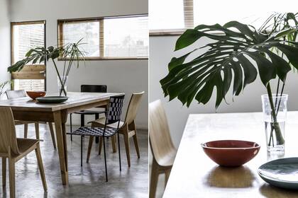 En este comedor se intercalan sillas de distintos diseños que aportan dinamismo. Sobre la mesa de madera, un simple pero efectivo florero incorpora hojas naturales que suman color y frescura