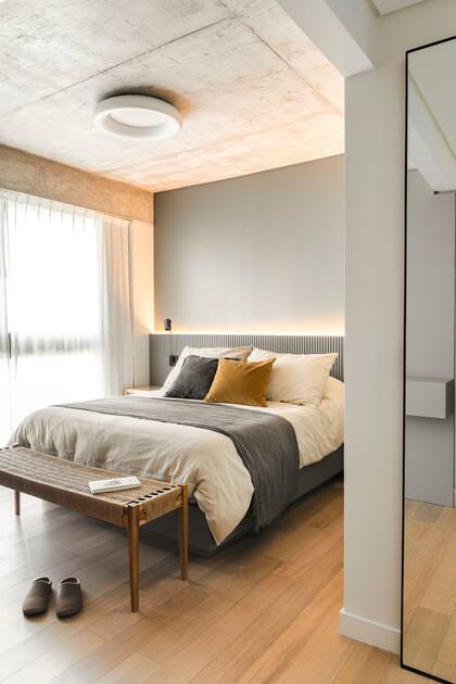 En este dormitorio diseñado por Sheila Burzstyn, el edredón crudo se acompañó de almohadones en terciopelo. El gris acompaña los tonos del departamento mientras que el detalle en mostaza suma cálidez.