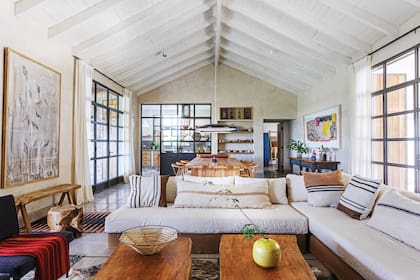 En este living comedor pensado como una suerte de gran vagón, la división vidriada separa la cocina sin aislarla.