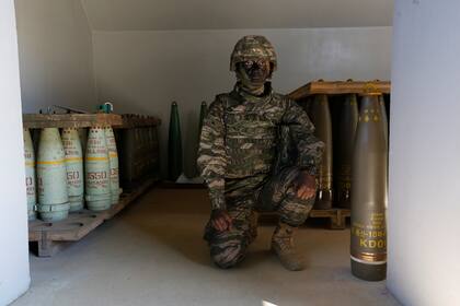 Un marine posa junto a proyectiles de artillería pesada