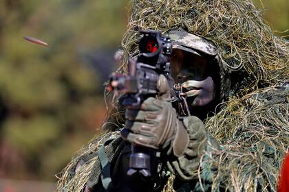 Un soldado con camuflaje vegetal dispara su arma. En la toma la bala queda congelada pese a la altísima velocidad de salida