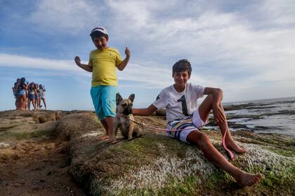 Mona, una bulldog frances de 1 año posa con sus duenos Augusto y Felipe