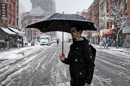 Un hombre cruza una calle cubierta de nieve, bajo una tormenta en plena primavera