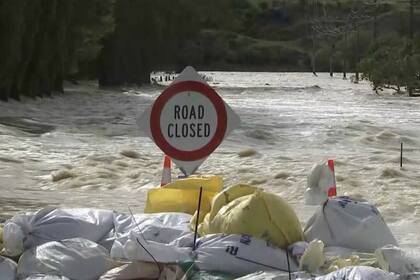 En Gore, una ciudad en Southland, bolsas de arena intentan contener el agua y un cartel avisa "camino cerrado"