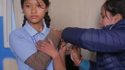 En Katmandú, Nepal, una estudiante nepalí recibe una dosis de la vacuna contra el virus del papiloma humano (VPH) en una escuela local