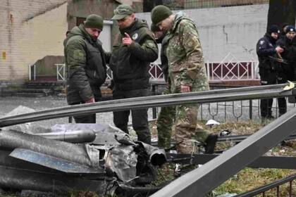 En Kiev, la policía y el personal de seguridad inspeccionan los restos de un proyectil en una calle.