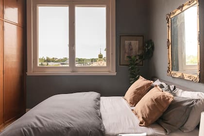 En la cama, almohadones de tussor color habano (Mercedes Segura), espejo vintage con marco barroco dorado a la hoja y obra de arte de Casiana Flores Pirán.