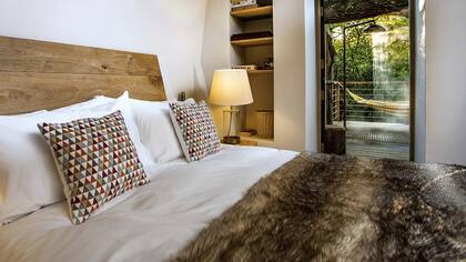 Todo el confort, pero contenido, para revivir esa sensación de ser chiquitos y estar bien abrigados. Las paredes gruesas protegen ventanas y puertas. Ésta, especialmente tentadora, lleva a la ducha al aire libre junto a una hamaca paraguaya.