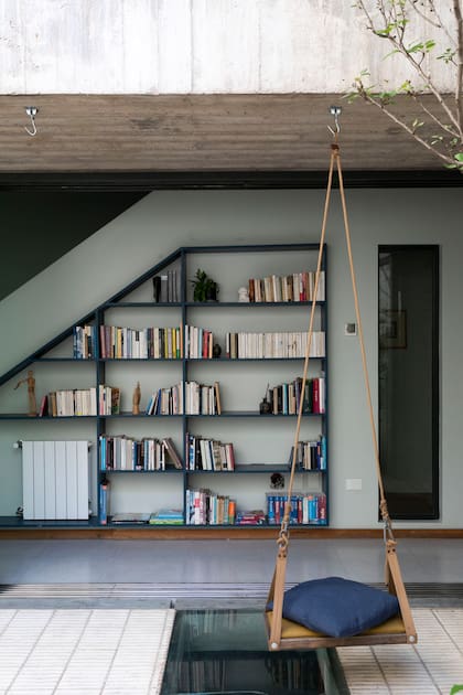 En la casa B, la estructura de hierro azul quedó expuesta, dibujando un trapecio sobre la pared gris claro.