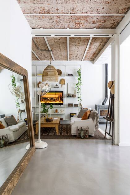 En la circulación, apoyado en el piso, ubicaron un espejo enorme encontrado en la calle y que se restauró. Biblioteca flotante de hierro con estantes de vidrio y chapa (Estudio Cántaro Bardó), botellas de cerámica blanca (Antes Pella), jarrones de cerámica roja (Apatheia).