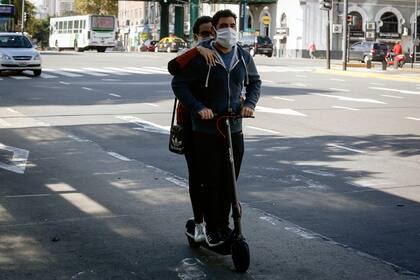 Una pareja en monopatín por una avenida de la ciudad