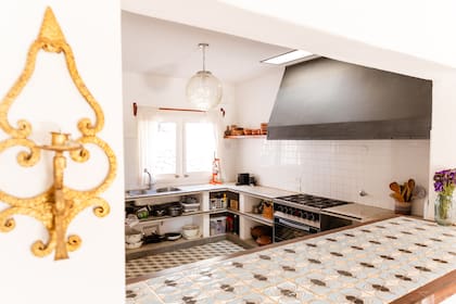 En la cocina conectada con el área social se destacan la gran campana de hierro hecha a medida y la barra con cerámicas artesanales jujeñas (Talara Mayólicas)