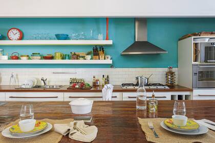 En la cocina, piso pintado de blanco, luminarias con forma de bola, enorme isla, mesada de lapacho y alzada de azulejos ‘Subway’.