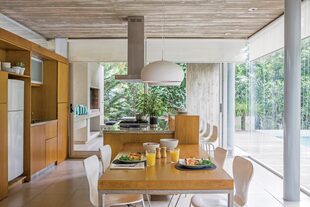 En la cocina se alinean mesa, isla y la parrilla en la galería. Campana de acero inoxidable (TST).