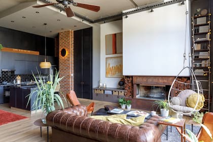 En la columna de la cocina, aplique ‘Eclipse’ (Iluminación Online). Sillón ‘Chesterfield’ de cuero (Fradusco) con almohadones (Carrefour).