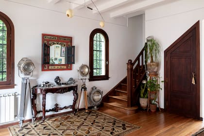 En la entrada, alfombra mid century, reflectores de aluminio facetado, un dressoir de guindo con tapa de mármol y espejo antiguo importado de Indonesia. El toilette se ubicó en el bajoescalera