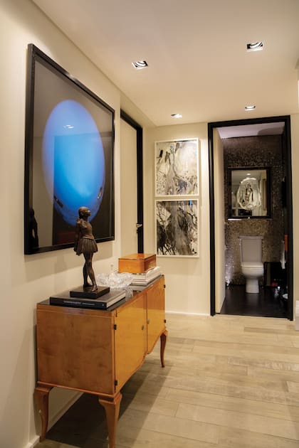 En la entrada de su departamento, que Regina decoró con exquisitez y mucho arte, una reproducción de una famosa escultura de Degas da la bienvenida. Detrás de ella, vemos una fotografía de Axel Straschnoy.