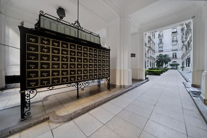 En la entrada del emblemático Palacio Los Patos, el histórico mueble de casillas de correo recibe a los visitantes, enmarcado por la arquitectura clásica y la vista hacia el patio central.