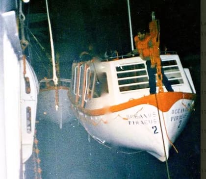 En la foto, uno de los tripulantes filipinos que había permanecido a bordo tratando de bajar un bote salvavidas colgado en el costado de babor del barco