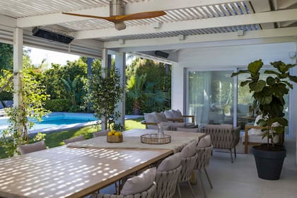 En la galería se hizo un techo tipo pérgola con caños rectangulares que arman una grilla. La mesa en madera maciza, diseño del Estudio, se acompañó con unas sillas importadas, igual que el ventilador de techo.