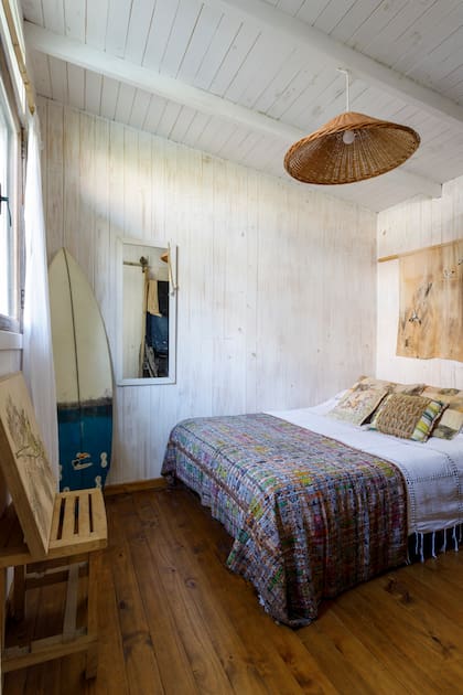 En la habitación del hijo de Marina, un banco de madera hecho por él mismo, su tabla de surf, un cubrecama comprado en Brasil y una obra de su madre sobre la cabecera.